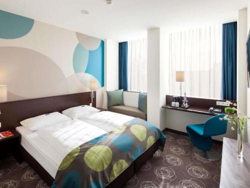 a bedroom with a bed and a desk and a chair at Webers Hotel im Ruhrturm Essen by Accor in Essen