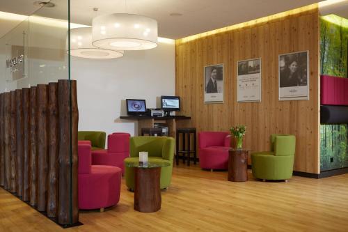 a waiting room with colorful chairs and tables at Mercure Hotel am Messeplatz Offenburg in Offenburg