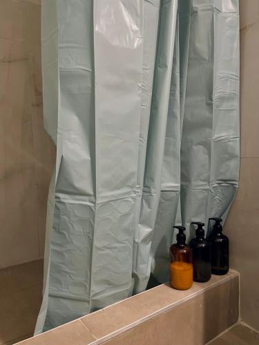 three bottles sitting on a shelf next to a shower curtain at Epanomi SunSet Loft in Epanomi