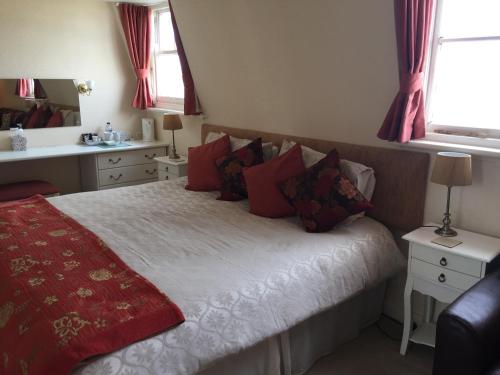 a bedroom with a bed with red pillows at The Chatsworth in Weymouth