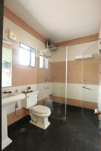 a bathroom with a toilet and a glass shower at Western Valley Resorts Ooty in Ooty