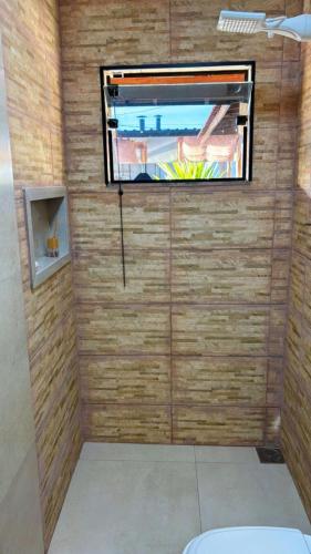 a room with a tv on a wall with a window at Chácara pôr do sol in Araçoiaba da Serra