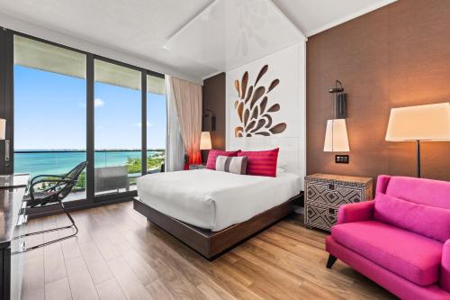 a bedroom with a bed and a pink chair at Kimpton Seafire Resort + Spa by IHG in West Bay
