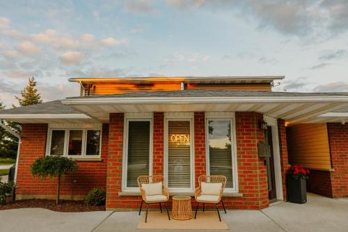 a red brick house with three chairs and a table at Manitoulin Inn in Mindemoya