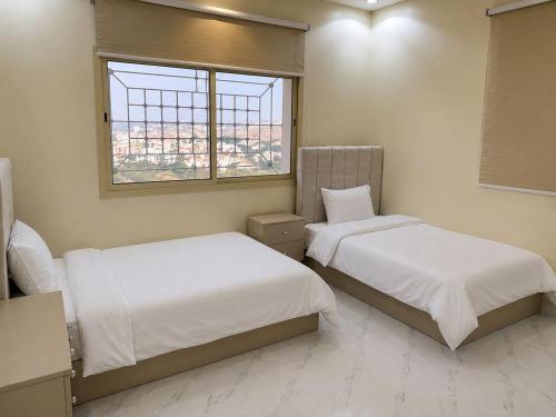 two beds in a room with a window at Highland Residence Al namas in Lahbey