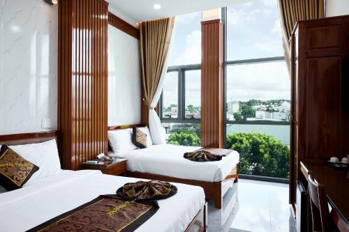 a hotel room with two beds and a large window at Phố Núi 2 Hotel in Pleiku