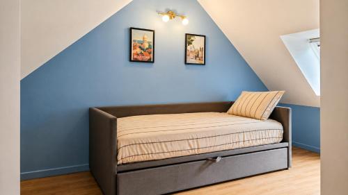 a bed in a room with a blue wall at Maisonnette en duplex avec Jardin-Babyfoot et Billard in Outreau