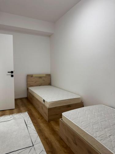 two beds in a room with white walls and wooden floors at Modi Living Apartment in Skopje