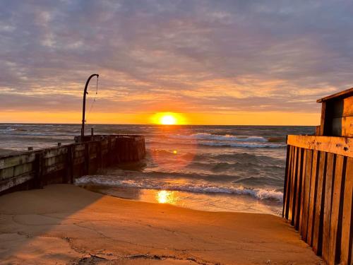 a sunset on the beach with the ocean and a pier at The SeveraLena, your Tawas Point destination! in East Tawas