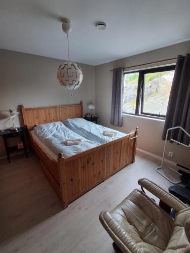 a bedroom with a large wooden bed and a chair at Fjordhytte-24 in Bøvågen