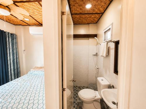 a bathroom with a toilet and a bed at Gloria's Home Stay in Oslob