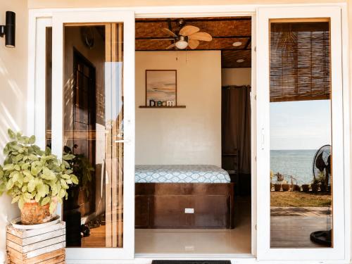 a room with a window with a bed and the ocean at Gloria's Home Stay in Oslob