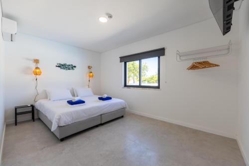 a white bedroom with a bed and a window at Vivenda Vilhegas in Albufeira
