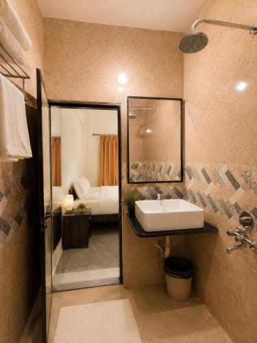 a bathroom with a sink and a mirror and a bed at Coutinho Guest House in Panaji