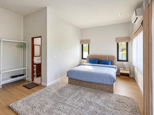 a bedroom with a bed with blue pillows and a rug at Sherlock Home Pool Villa Krabi in Ban Chong Phli