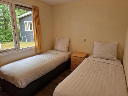 two beds in a room with a window at De Tien Heugten in Schoonloo