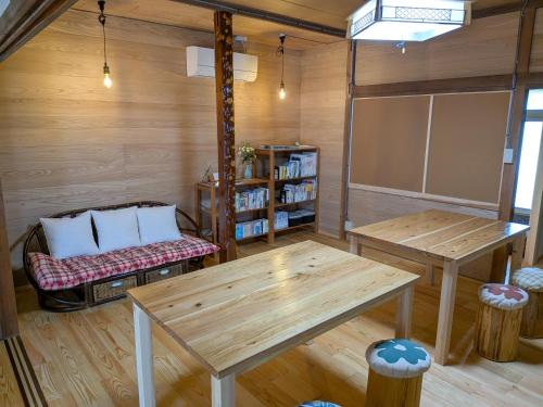 a room with two tables and a bench in a room at おかえりヒュッテ in Komagane
