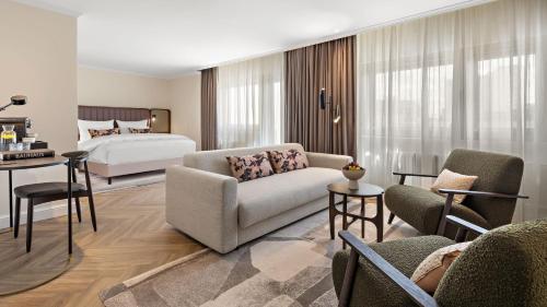 a living room with a bed and a couch and chairs at Bristol Berlin, Vignette Collection by IHG in Berlin