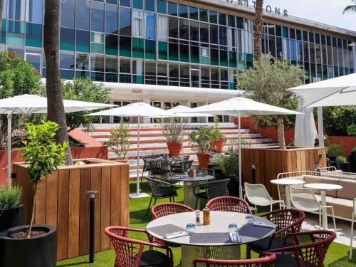 an outdoor restaurant with tables and chairs and umbrellas at Novotel Nice Centre Vieux Nice in Nice