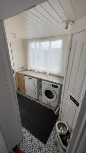 a small bathroom with a washing machine and a window at Donrae in Portree