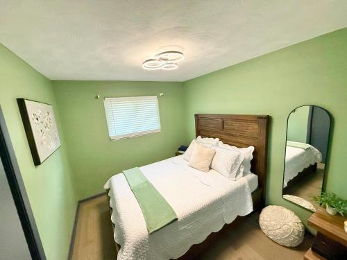 a green bedroom with a bed and a mirror at Delightful 3 Bd Home with King size bed, hot tub, playground! in Indianapolis