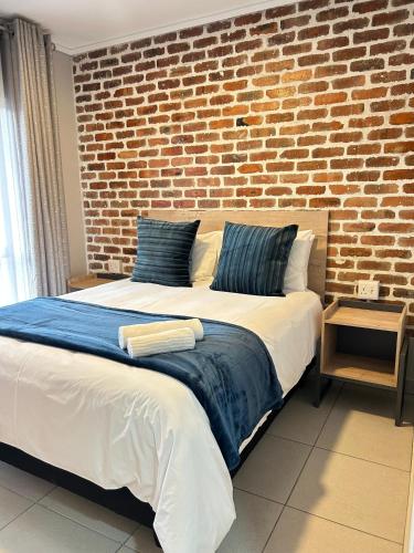a bedroom with a large bed with a brick wall at 166 Green valley in Boschrand