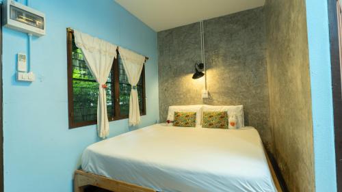 a bedroom with a white bed with a window at Retro At Phra Sing Guest House in Chiang Mai