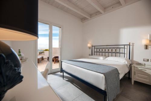 a white bedroom with a bed and a balcony at Hotel Boutique Il Castellino Relais in Vieste