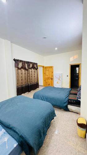 two beds in a bedroom with blue sheets at CLOUD HEIGHTS COTTAGE NATHIA GALi in Nathia Gali