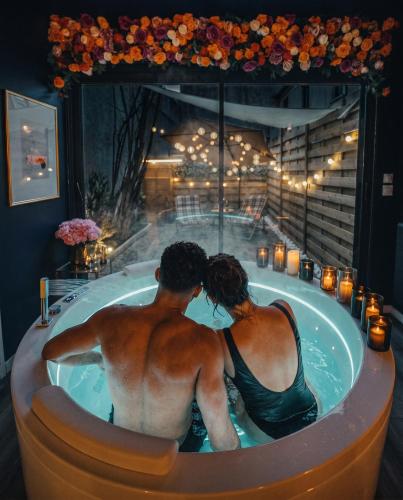 a man and a woman sitting in a bath tub at L'Eure de Luxure Loveroom Suite in Normandy in Évreux