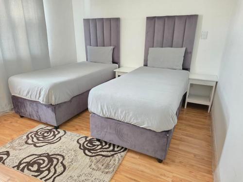 two beds in a small room with a rug at Vinview 2 bedroom apartment in Swakopmund