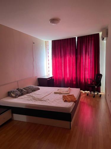 a bedroom with a large bed with pink curtains at Апартамент София in Golden Sands
