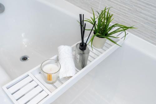 a bathroom with a white tub with plants and towels at Meadow Park Villas in Manchester
