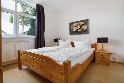 a bedroom with a wooden bed with white sheets and a window at Haus 17 in Röbel