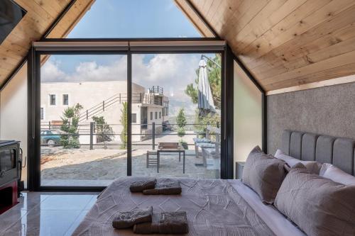a bedroom with a bed with a large window at Maison Jwar - Luxury A-Shape Cabins - A Unique Summer Getaway in Ḩārat at Taḩtā