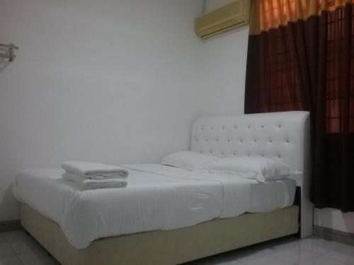 a bed with white sheets and pillows in a room at Anjung Homestay in Sepang