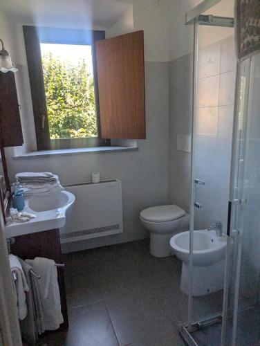 a bathroom with a toilet and a sink and a window at Monterosa Apartment in Morghengo