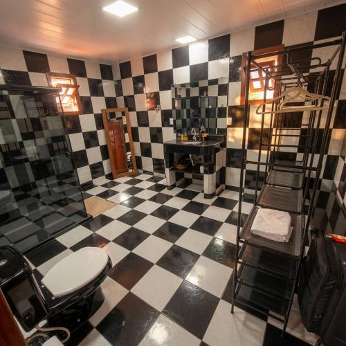 a bathroom with a toilet and a black and white checkered floor at Residência Thomas in Itacaré