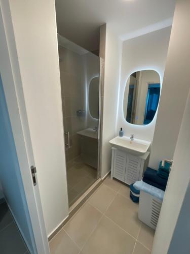 a bathroom with a shower and a sink and a mirror at Blue sunset - Appartement avec vue mer in Papeete
