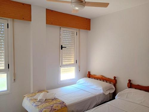 two beds in a room with two windows at Edificio Mirasierra in Oropesa del Mar