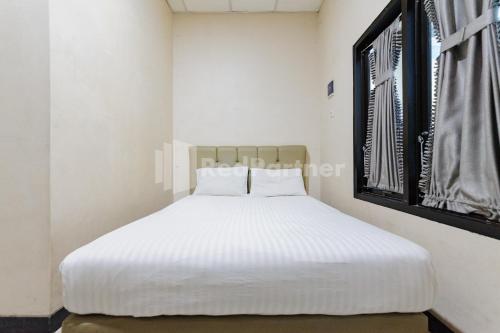 a white bed in a room with a window at Wisma Merdeka Syariah RedPartner in Palembang