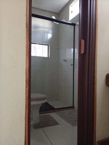 a bathroom with a toilet and a glass shower door at Hospedaria Portal das Montanhas in Ibicoara