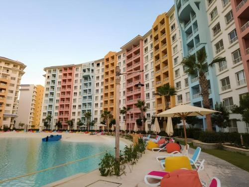 a swimming pool with chairs and umbrellas and buildings at بورتوجولف portogolf in El Alamein