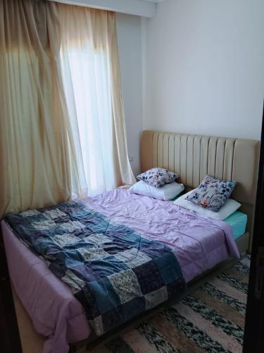 a bed with a quilt and pillows in a bedroom at بورتوجولف portogolf in El Alamein