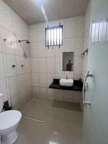 a bathroom with a toilet and a sink and a mirror at Hostel Coimbra Araçagi in Macajatuba