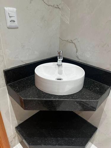a white sink on a black counter in a bathroom at Arruda UMARI in Benevides