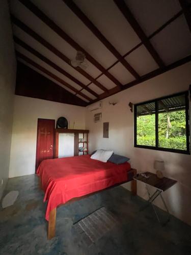 a bedroom with a red bed and a window at Dolphin Quest Apartment #1 in Pavones