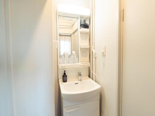 a bathroom with a sink and a mirror at By The Tree Room in Amami