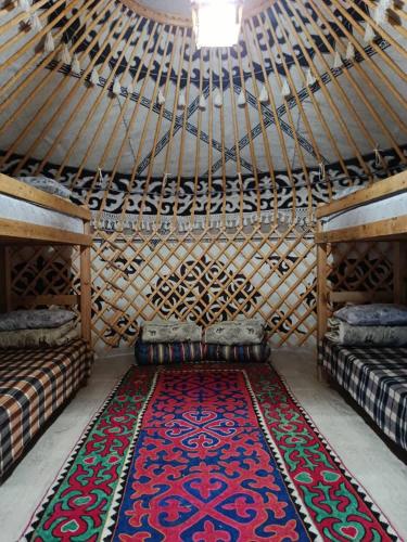 a room with two beds and a rug in a yurt at 40 Rays Yurts in Bosteri