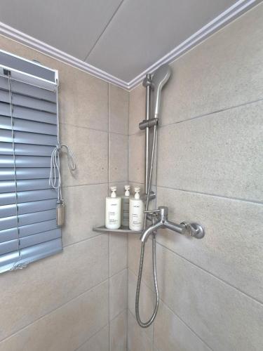 a shower in a bathroom with two bottles on a shelf at 원하우스 in Seoul